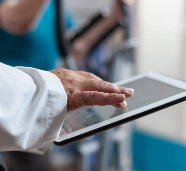 Close up of doctor using digital tablet with touch screen at physical recovery clinic. Medical worker holding modern device and technology to help patient with workout and fitness